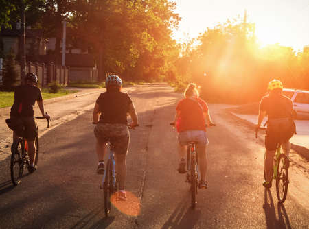 A group of people ride bicycles on the road at sunset. Active hanging out with friends.の写真素材