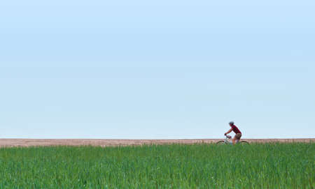 Girl on a bicycle in the field against the sky. Minimal concept.の写真素材
