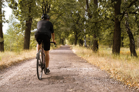Cyclist on a gravel bike rides along country road with pits. Outdoor sport activity.の写真素材