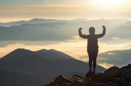 Silhouette of strong woman on mountain peak flexing her muscle demonstrating self-confidence and...