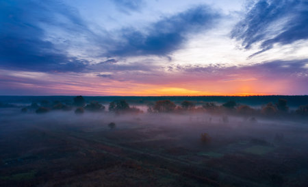 Morning landscape at sunrise with fog in a countryside field with beautiful cloudy sky.の写真素材