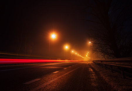Empty highway with light trails from passing car at night.の写真素材