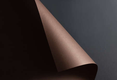 Abstract background with brown curled sheet of paper on a gray wall. Copy space.の写真素材