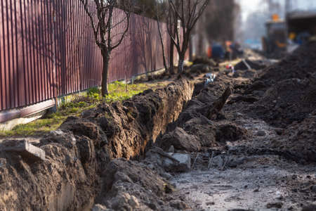 Earthwork. A deep long trench dug in the ground for laying cables, pipes. Telecommunications industry.の写真素材