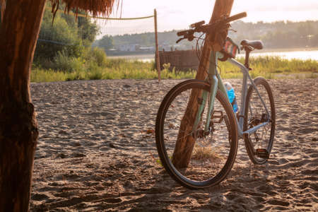 Road bike on a sandy beach by the river at sunrise. Active and sporty morning concept.の写真素材