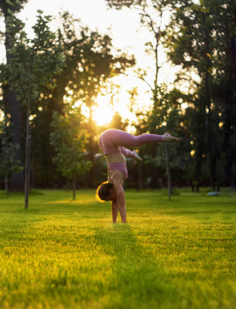 Young girl practicing yoga in the park at sunset. Meditation and relaxation concept.