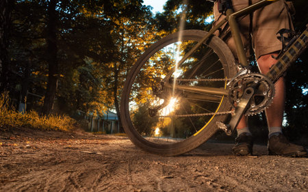 Cyclist standing with bicycle on dirt road at summer sunny day.