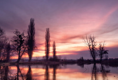Dramatic landscape with beautiful glowing sky with clouds over a lake at sunset. Beauty of nature's...