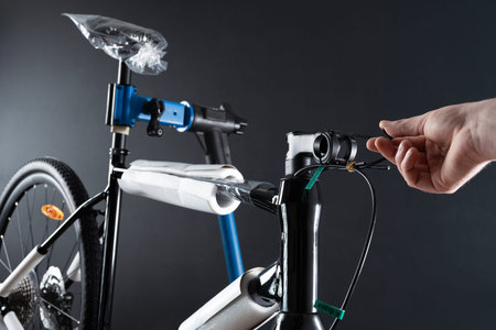 Mechanic adjusts a brand new bicycle on rack against dark background. Bike service.