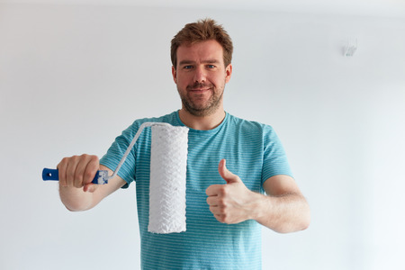 Smiling man holding a roller in front of himの写真素材