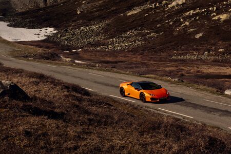 Rjukan, Norway. 04.06.2016: Yellow Lamborghini Huracan driving quickly along a road in a mountainous landscapeのeditorial素材