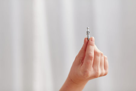 A woman's hand, holding a screw for furniture assembly. Concept for self-contained, easy furniture assembly.の写真素材