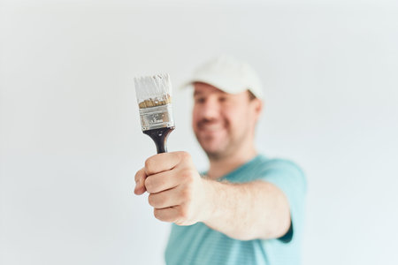 Smiling man holding a roller in front of him The idea of painting the apartment. The face is out of focusの写真素材