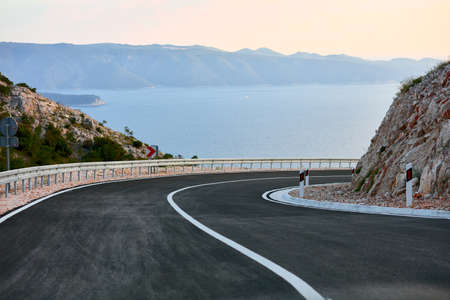 A bend in an empty road on the seashore. Island of Brac, Croatia. New, recently built asphalt road.の写真素材