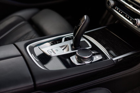 Automatic gear shift knob in a modern sports limousine car. Black car interior.
