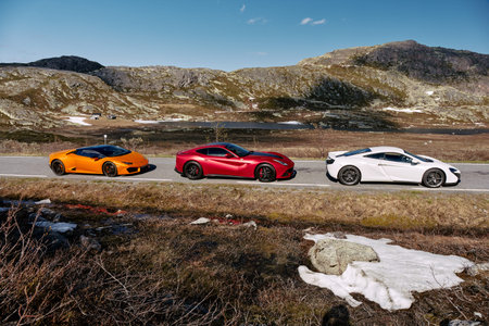 White Mclaren 650s, Red Ferrari f12 and Yellow Lamborghini Huracan. Cars are standing in a row on the road. Rjukan, Norway. 04/06/2016のeditorial素材
