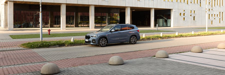 BMW X1 25e, hybrid, plug in car, parked next to a modern building. The total power of both engines...