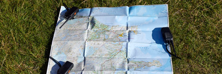 Folded map of Iceland laid out on grass with three walkie-talkies. Planning a trip, communication,...