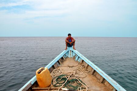 Fisherman in boat takes half sky half seaの写真素材