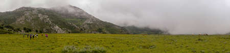 Big panorama of hikers by valley with coming fogの写真素材