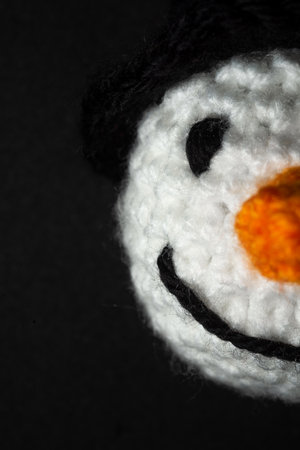 Portrait of Amigurumi Snowman crocheted or knitted stuffed toy on black backgroundの写真素材
