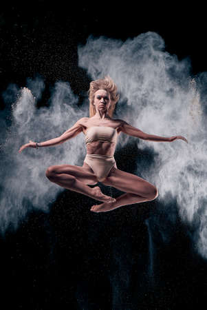 The dance of the body, girl performing with cloud of flour, black backgroundの写真素材