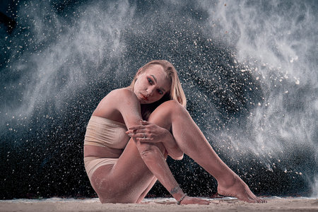 Portrait of a blonde girl in underwear with flour . background is black
