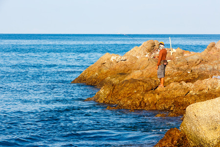 A fisherman catches a fish on spinning. Andaman sea. Thailand.の写真素材