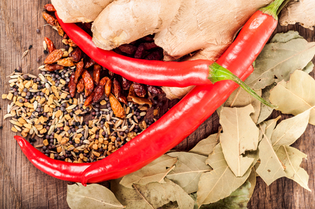 Seasoning concept - Assortment of fresh and dry spices on wooden background, chili, bay leaves, ginger, coriander, seedsの写真素材