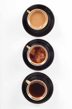 Three cups of coffee with black, white and flowing milk on white backgroundの写真素材