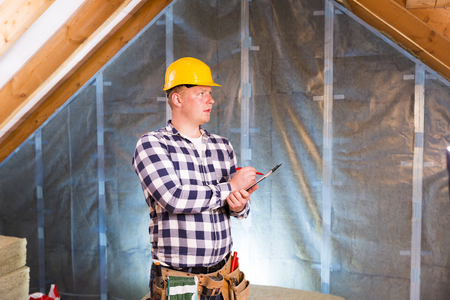 Handyman with a tool belt planning work, making to do list. House renovation service.の写真素材