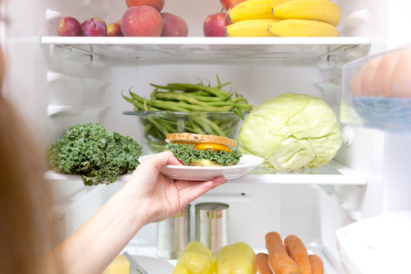 Woman taking a healthy sandwich out of the fridgeの写真素材