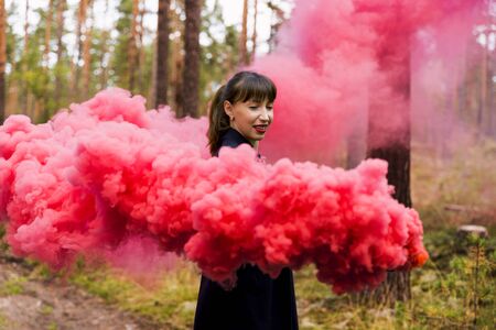 Young woman in forest having fun with red smoke grenade, bombの写真素材