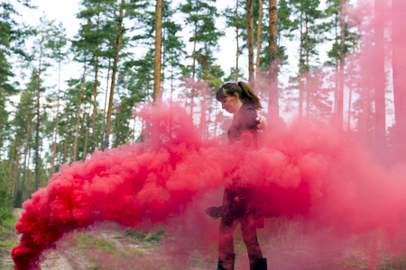 Young woman in forest having fun with red smoke grenade, bombの写真素材