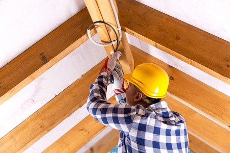 Electrician working with wires at attic renovation siteの写真素材