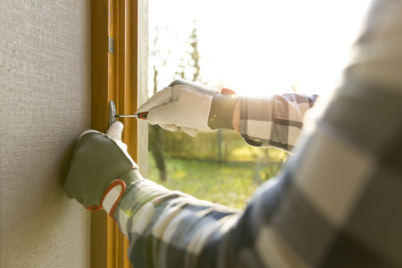 Handyman fixing the window with screwdriverの写真素材