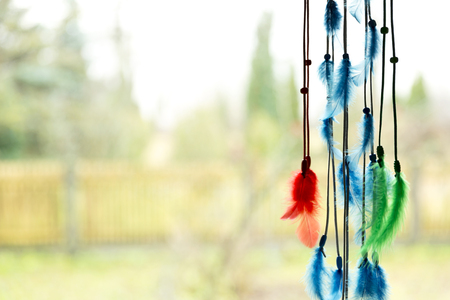 Beautiful dream catcher by a window with blue, green and red feathersの写真素材