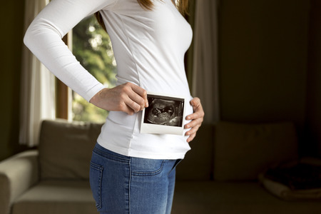 Pregnant woman expecting newborn and holding ultrasoundの写真素材