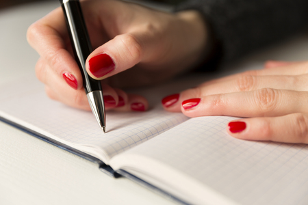 Female hands with pen writing on notebook. Diary, plans, journalistの写真素材