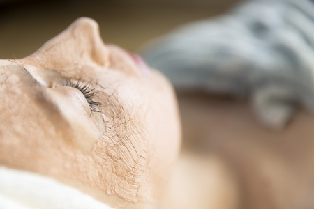 Beautiful young woman having a facial cosmetic treatment with clay face mask. Skin care conceptの写真素材