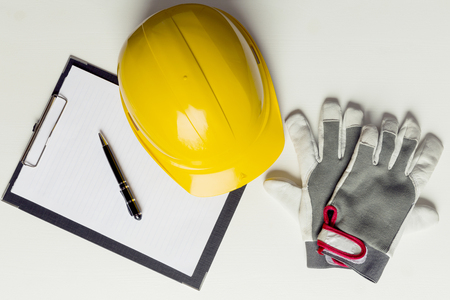 Contractor concept background. Yellow hard hat helmet, construction gloves and notebookの写真素材