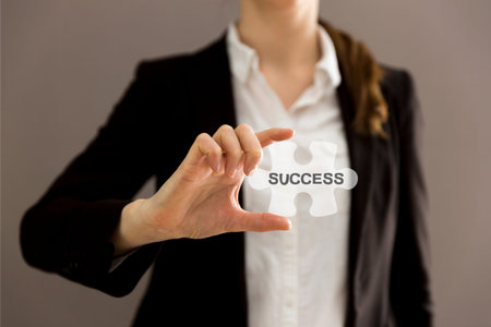 Business woman holding jigsaw puzzle piece with "SUCCESS" wording. Concept for business strength and success.の写真素材