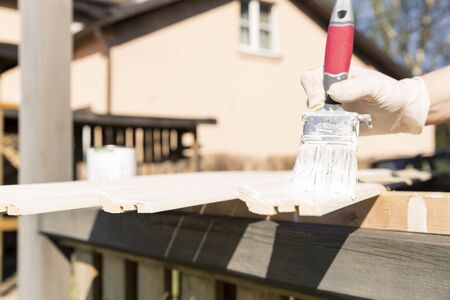 The process of painting a wooden lath outdoors. Home renovation conceptの写真素材