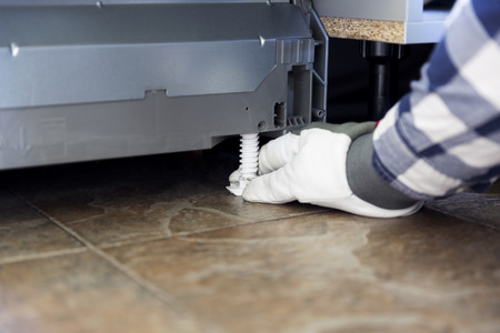 Handyman installing and adjusting dishwasher. Kitchen renovation and installation concept.の写真素材