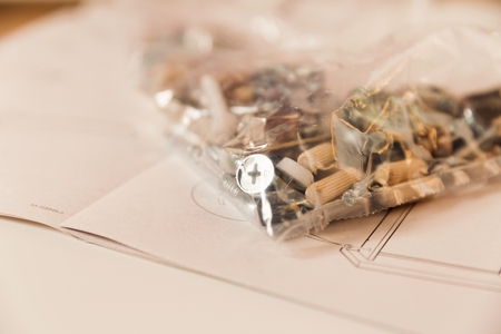 Furniture assembly. Group of furniture parts in plastic bag placed on instructions manual.の写真素材