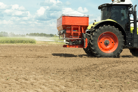 Tractor with sprayer trailer beside the cereal field. Heavy machinery for agricultureの写真素材