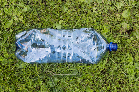 Crushed blue plastic bottle laying in grass. Pollution and environment conceptの写真素材