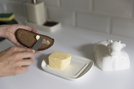 Woman smears butter with a knife on bread. A Healthy Eating Conceptの写真素材