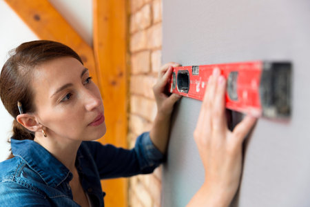 Home improvement. Beautiful women making a mark on wall with level.の写真素材