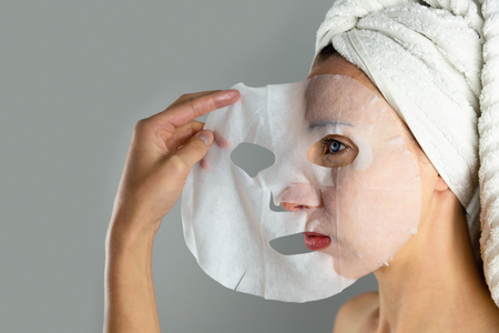 Beautiful women applying facial mask with moisturizerの写真素材